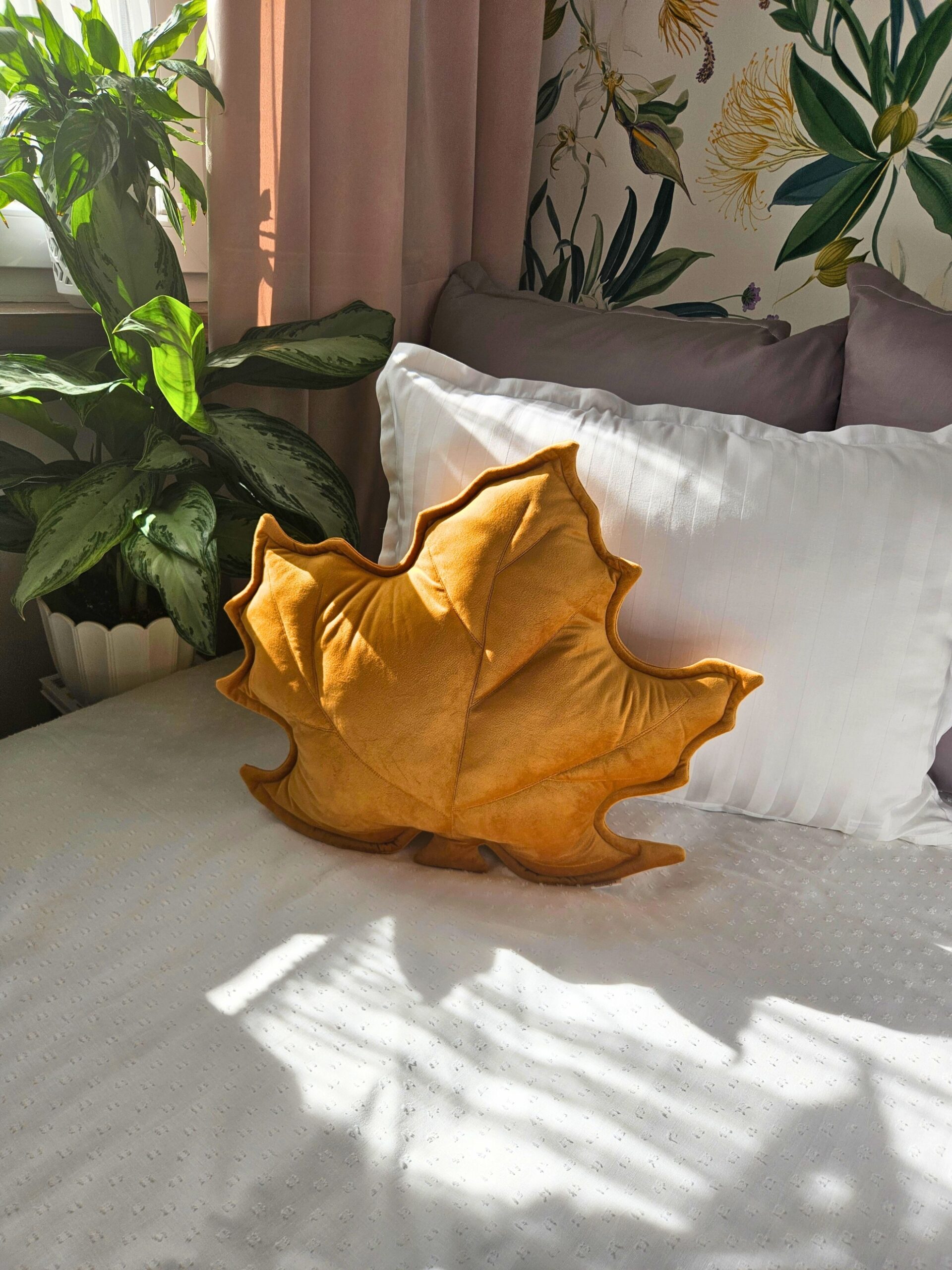 Musztardowa poduszka dekoracyjna w kształcie liścia klonu na szarej kanapie - sposób na przytulny salon.