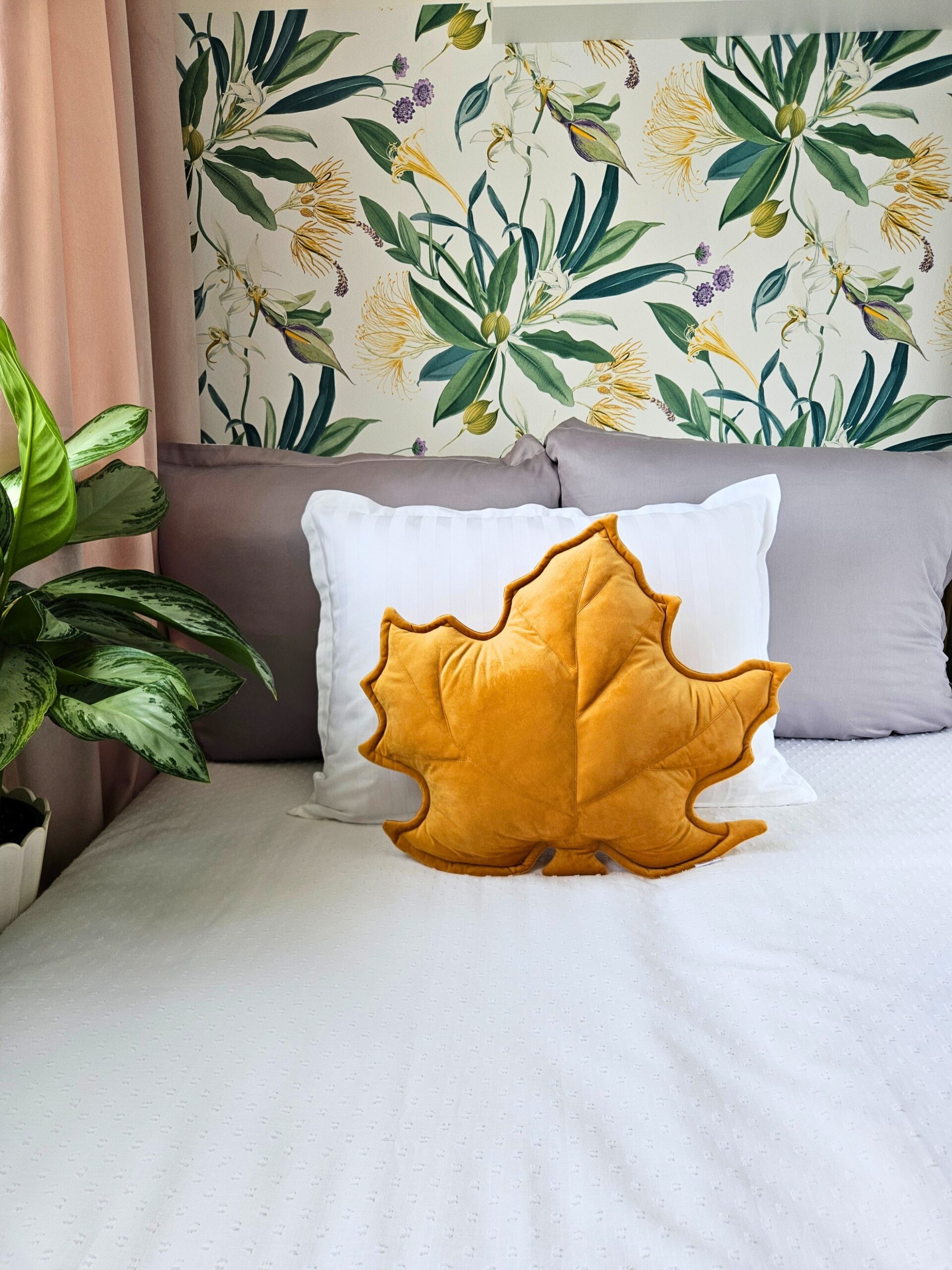 Musztardowa poduszka dekoracyjna w kształcie liścia klonu na szarej kanapie - sposób na przytulny salon.