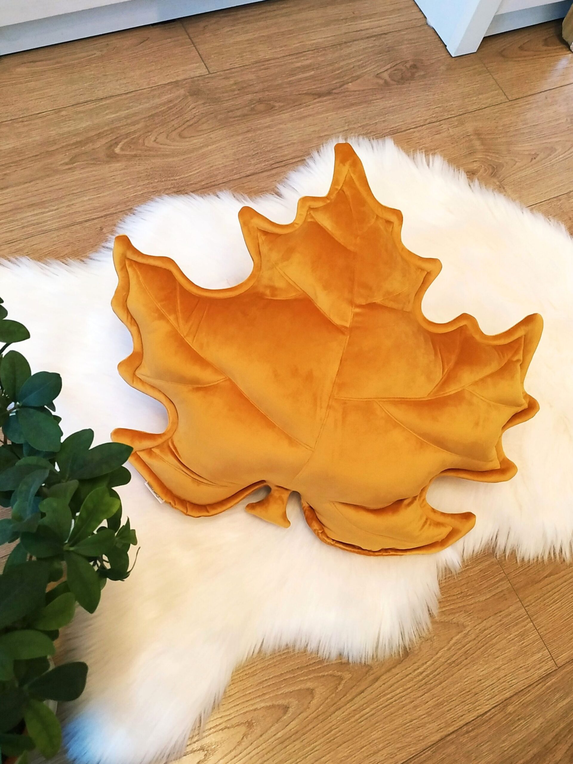 Musztardowa poduszka dekoracyjna w kształcie liścia klonu na szarej kanapie - sposób na przytulny salon.