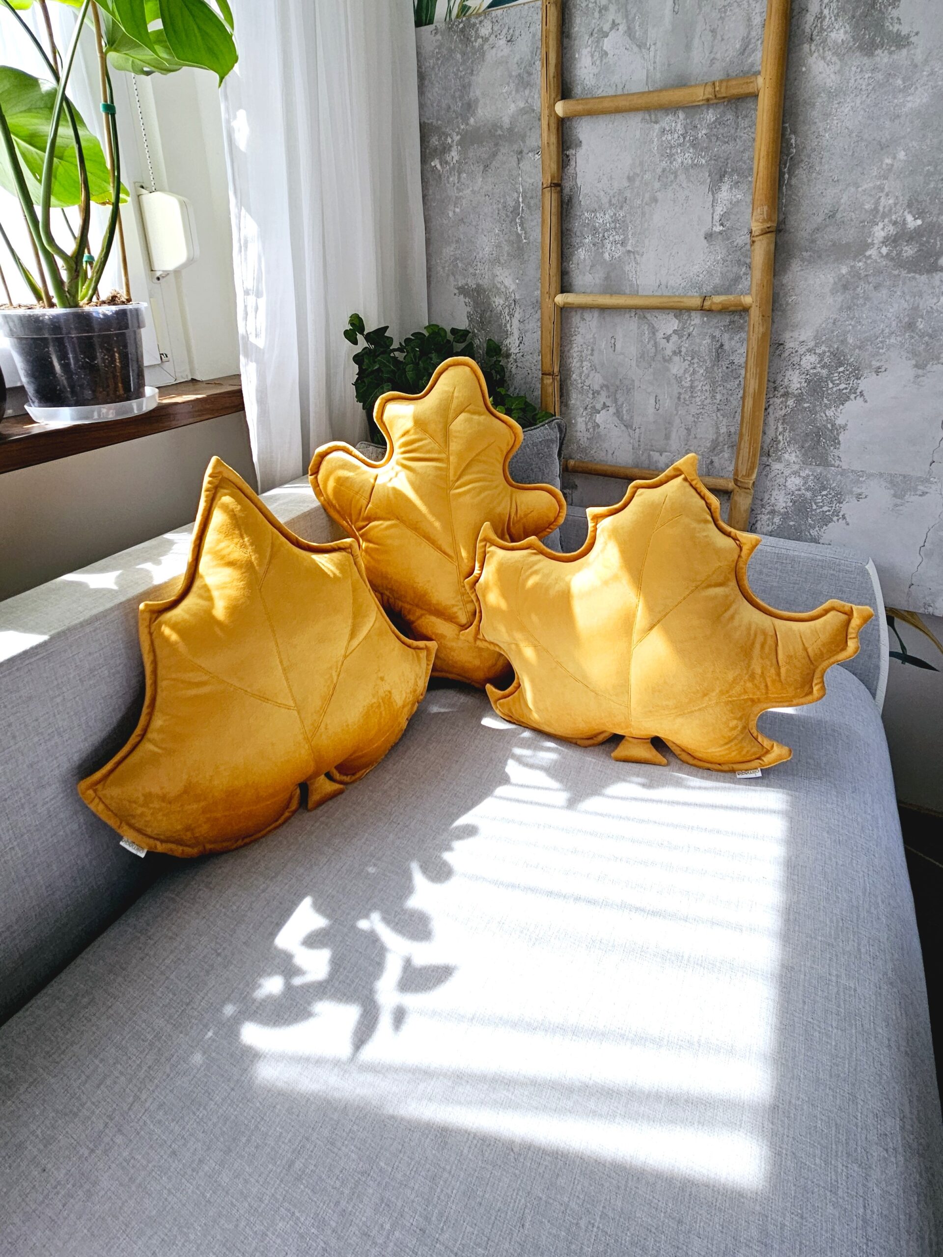 Zestaw 3 musztardowych poduszek dekoracyjnych w kształcie liści, idealny jako prezent na parapetówkę.