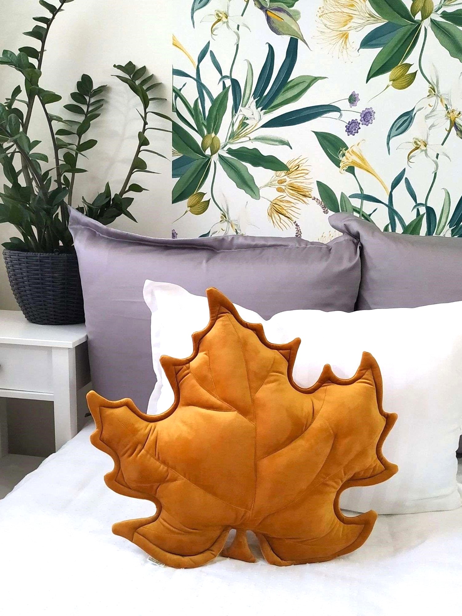 Musztardowa poduszka dekoracyjna w kształcie liścia klonu na szarej kanapie - sposób na przytulny salon.